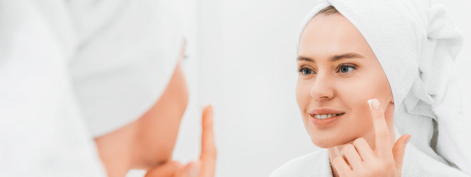 Woman applying face cream for glowing skin by Lapink